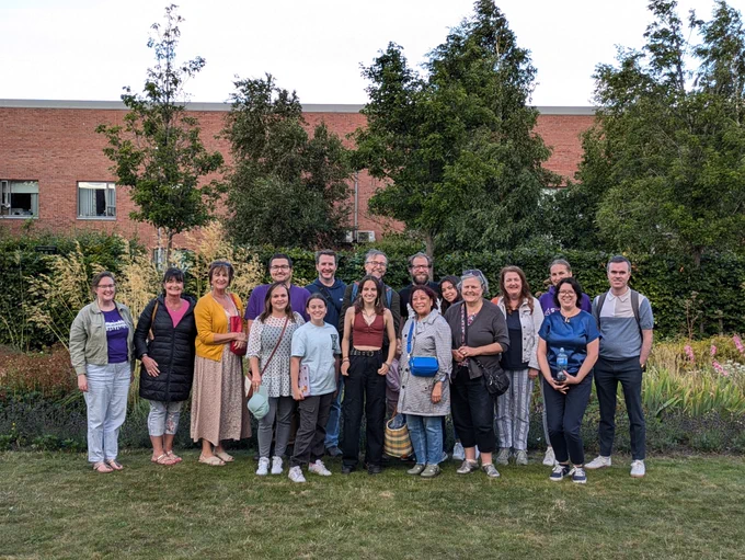 A large group of people with a garden behind them
