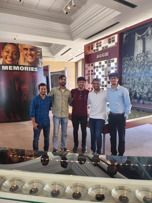 A group of Texas A&M students pose for a photo in front of a display case with Aggie Rings over the years at the Association of Former Students building.
