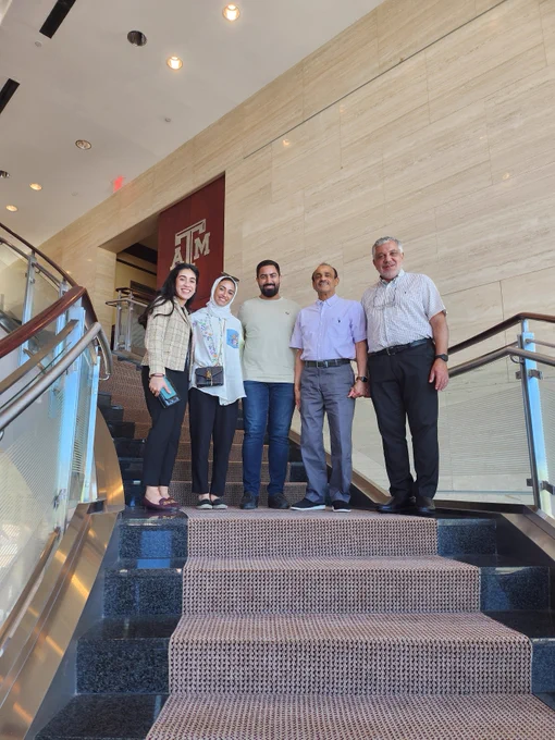 A couple of students and some family members pose for a photo on a staircase at the Texas A&M Association of Former Students building.