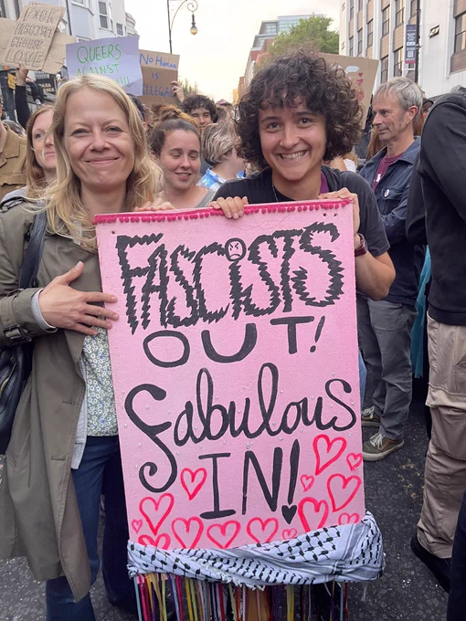 Sian Berry with an anti racist protestor with a handmade pink sign saying Fascists out, fabulous in!