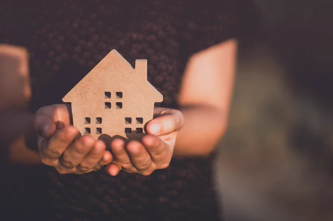A person holding a wooden house in their hands