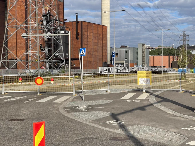 Flowfestivalin takia suljetun Vilhonvuorenkadun sulkevat aidat Suvilahdessa. Taustalla Hanasaaren voimala.