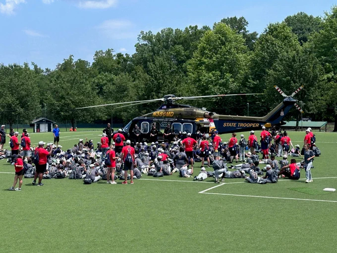 A large group of participants gather before a Maryland State Police helicopter for a law enforcement presentation. 