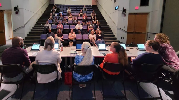 Panelists sitting at a table with people in the audience.
