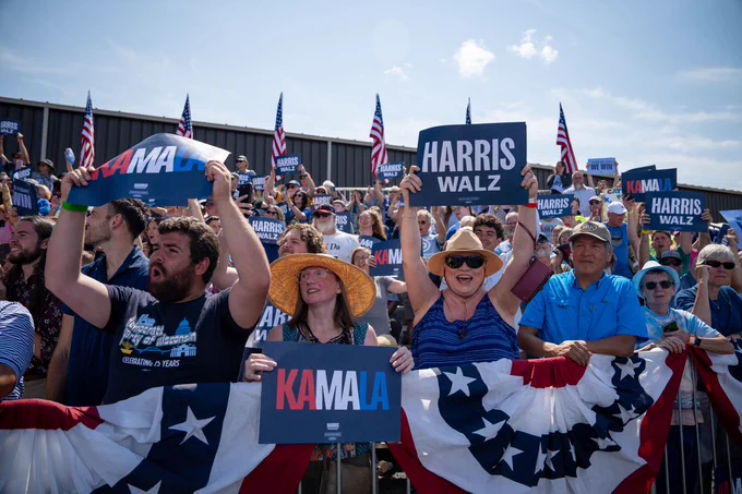 Rallygoers at the Harris-Walz rally in Eau Claire wave campaign signs.