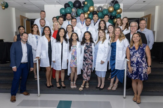 Group of Rush cardiac perfusion students and faculty posing for a photo at the white coat ceremony with balloons in the background.