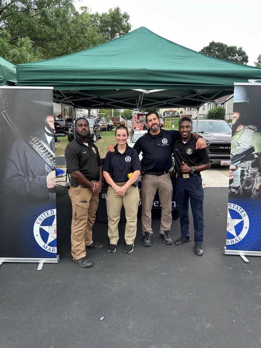 Two Deputy U.S. Marshals stand with two local law enforcement partners. 