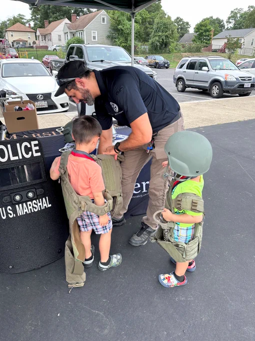 Two children try on tactical gear.