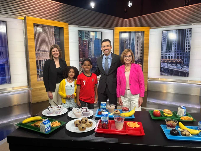 A group photo in front of school lunch trays on a table. 