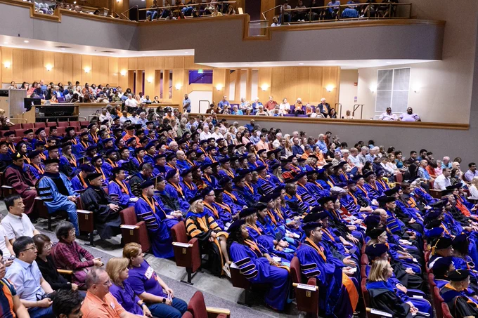 A group of doctoral degree recipients seated in an auditorium.