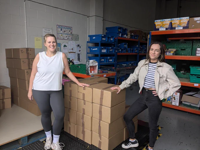 Two of the lovely IMA team with the boxes they packed up whilst volunteering at the foodbank