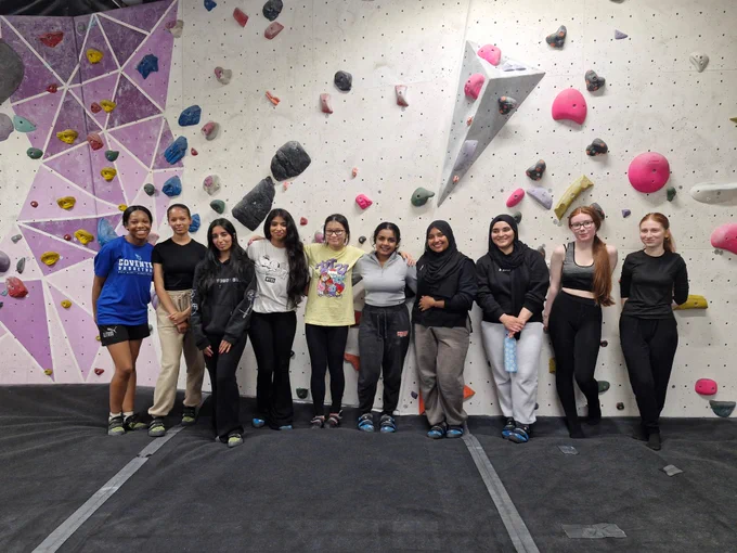 [Image shows ten students stood infront of a climbing wall smiling]