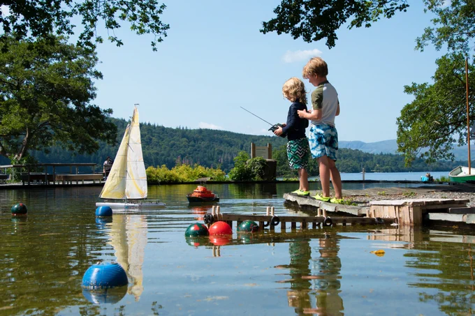Two children playing with model boats on the Boating Pond during a beautiful sunny day.