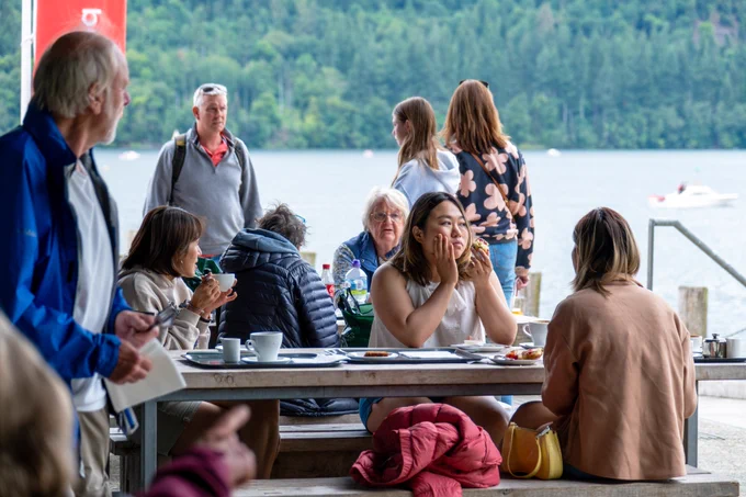 People enjoying the outdoor cafe area overlooking the lake at Windermere Jetty Museum.