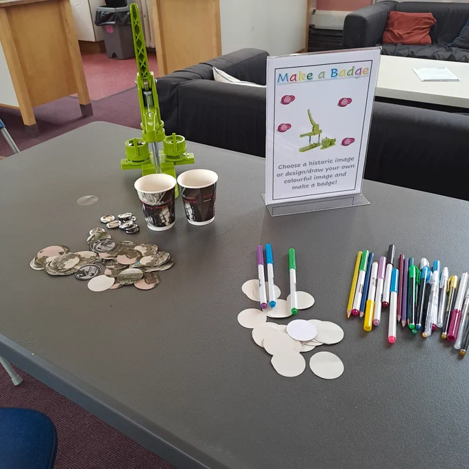 Badge maker with colored pens on the table 