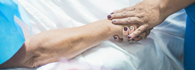 a person lying on a bed holding hands with another person