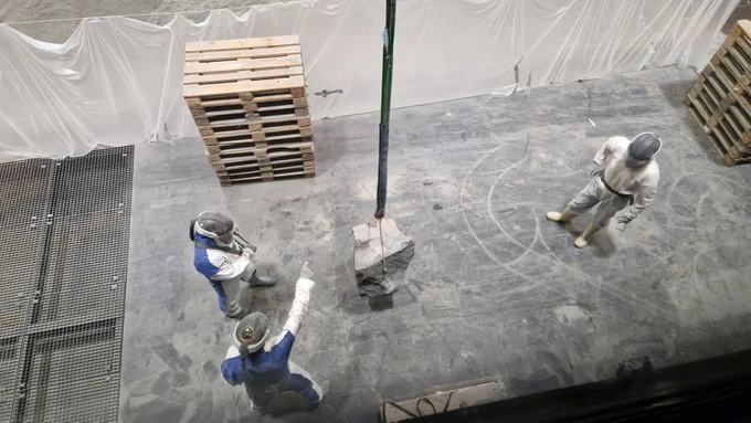 Gesteinsbrocken „am Haken“.
Mit einem Kransystem in der LUNA-Halle werden die schweren Gesteinsbrocken zu ihren vorgesehen Standorten transportiert. Bei den Arbeiten in der Halle müssen aufgrund des feinen Regolith-Staubs jetzt Ganzkörper-Schutzanzüge getragen werden.

Credit: DLR/ESA