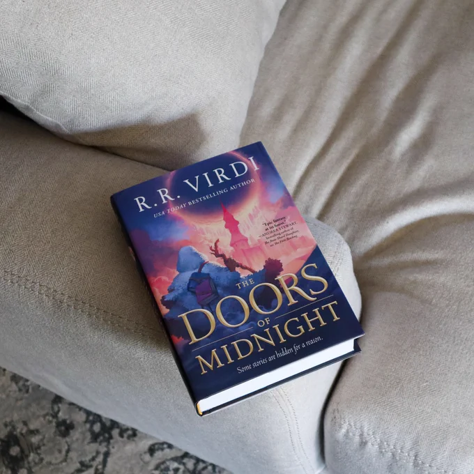 The Doors of Midnight by R.R. Virdi is on a grey armchair 