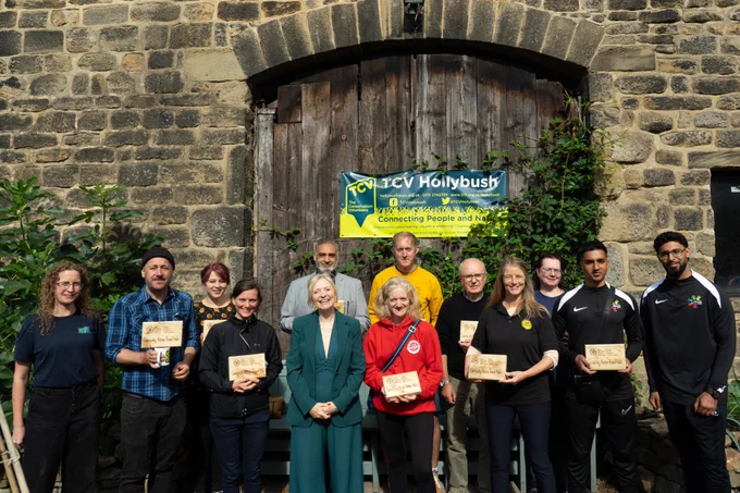 Tracy Brabin, Mayor of West Yorkshire stood in a group picture with people who have received funding, they are holding wooden plaques.