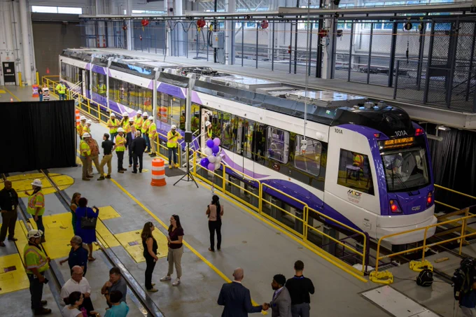 Maryland MTA's future Purple Line railcar resting on tracks surrounded by viewers in station.