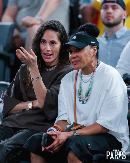 Sue Bird sitting next to Dawn Staley and gesturing at the court