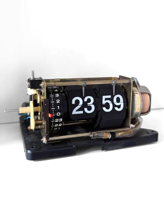 white background; electromechanical flip clock (mechanism, black plates, white numbers 23:59)