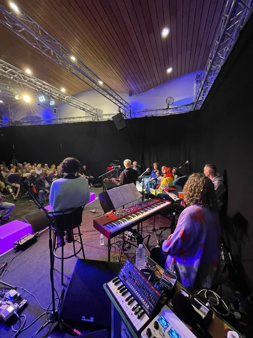 Photo from the stage, showing some musicians and instruments in front of an audience.