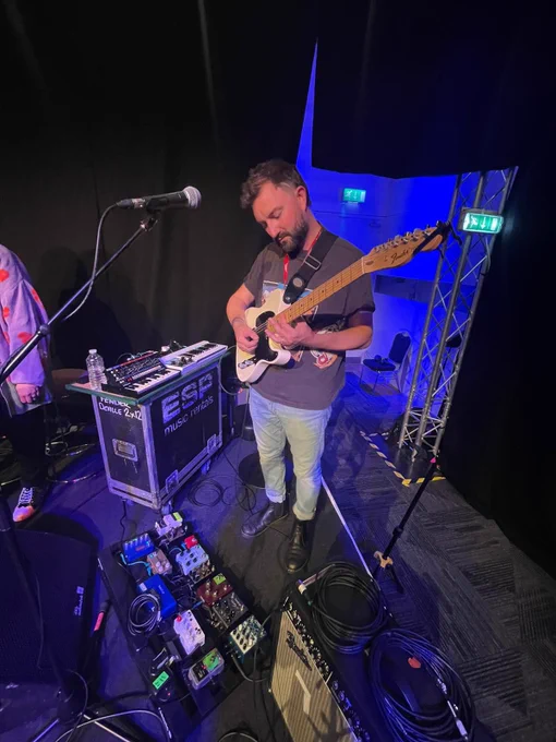 Stage image of musician aloud holding electric guitar.