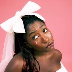 A Black woman looking wistful on a pink background