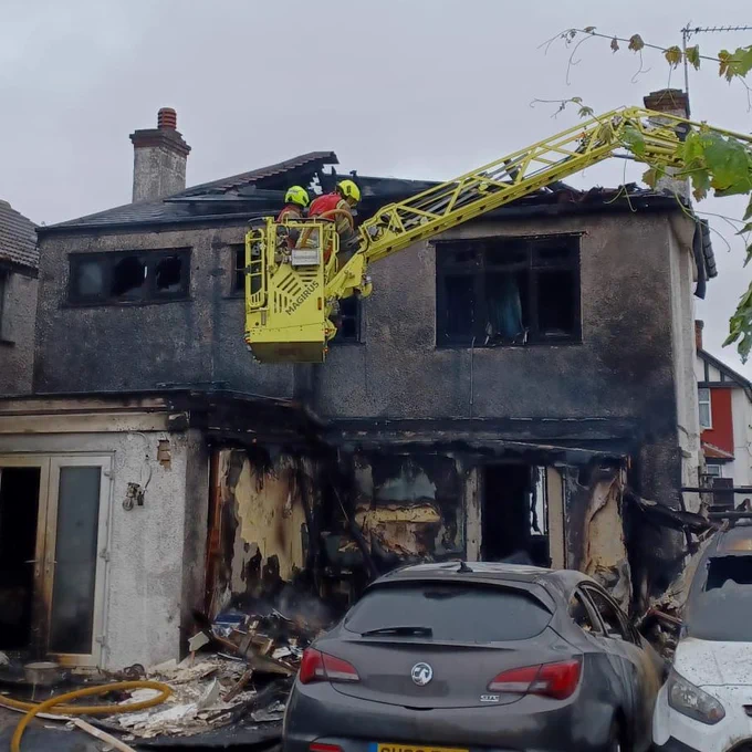 A turntable ladder at the window of a burnt out house