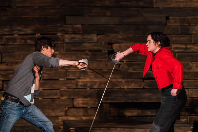 Two teenaged actors engage in a full-on swordfight onstage. They look focused, and they look awesome.