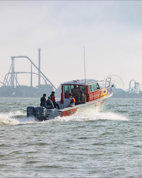BGSU Ziggy boat moves towards sandusky bay. Water testing kits are on board with 5 people sitting on the back of the boat. 