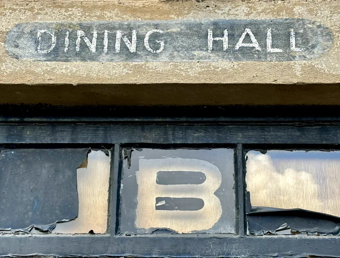 A close up photo of the sign above the door of the WW2 Dining Hall at Newbattle Abbey. Capital B stencilled onto the glass and the words Dining Hall stencilled onto the stone above.