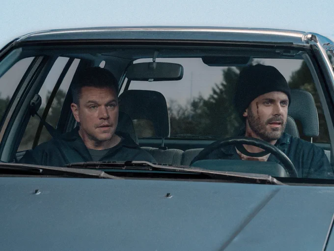 Still from The Instigators showing Matt Damon and Casey Affleck looking rough and shocked in a car.