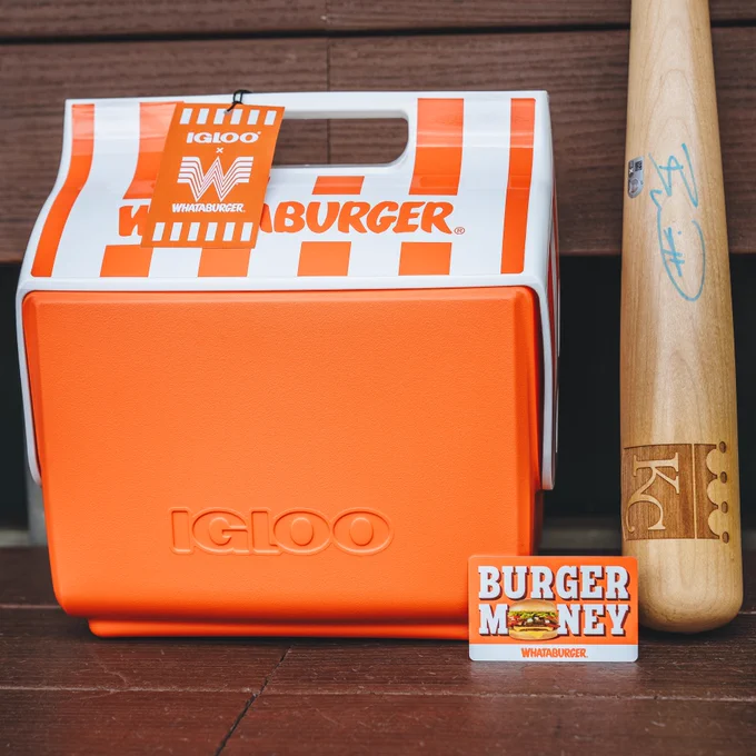 A photo of a Whataburger Igloo cooler, a Whataburger gift card, and a baseball bat signed by Bobby Witt Jr. on the bench in the Royals dugout.