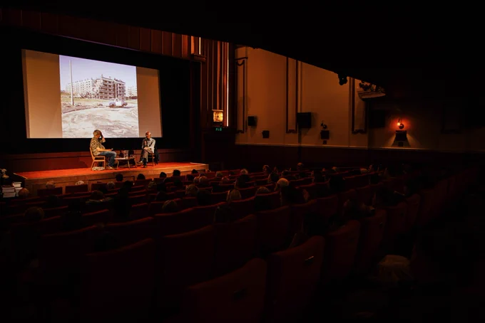 Peter Mitchell and Martin Parr sat on HPPH stage with audience in front of them and one of Peter Mitchell's photographs on the screen behind them.