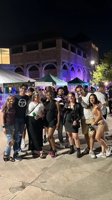 A group of students pose at an outdoor evening event.