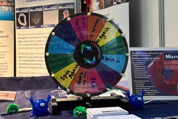A spinning, competition wheel on the RMS exhibition stand at emc2024. The wheel features coloured segments with prizes written on them.