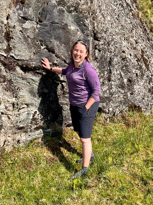 BGS' Kathryn Goodenough standing next to a rockface, with her hand on it. She is turned to the camera and is smiling.