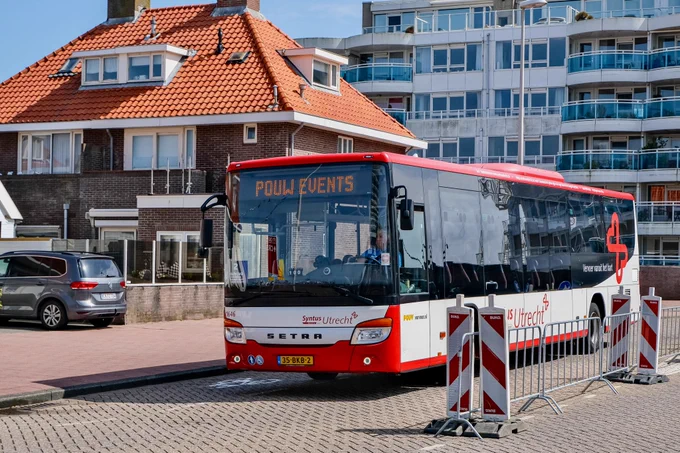 Crowds of people wearing rain gear walk, cycle, and ride the bus and train during the Dutch Grand Prix on a rainy day in Zandvoort.