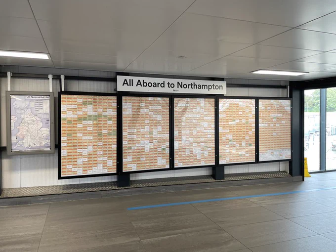 A wall that says “All aboard a to Northampton” with lots of tickets in cases but spaces between them with missing tickets.