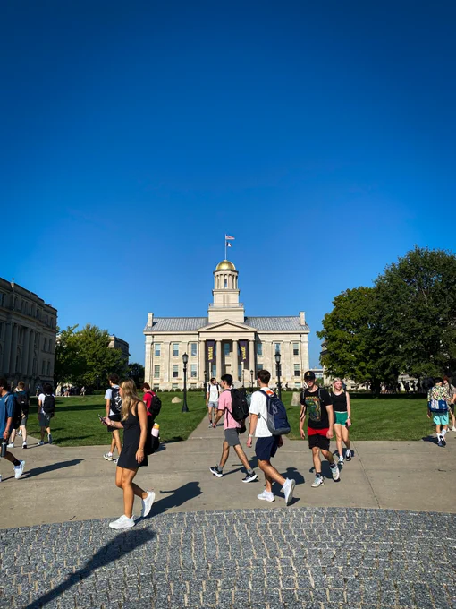 Photo of the Old Capitol Building at the Pentacrest, with the sidewalks filled with students walking to class on the first day of the fall semester