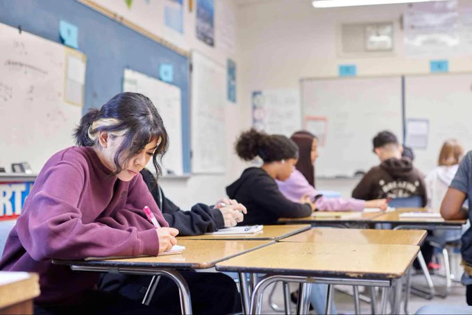 A high school classroom full of students working individually on paper.
