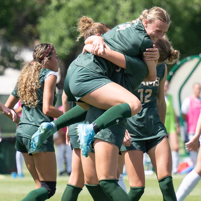 C S U soccer player Liv Stutzman jumping on a teammate and hugging them.