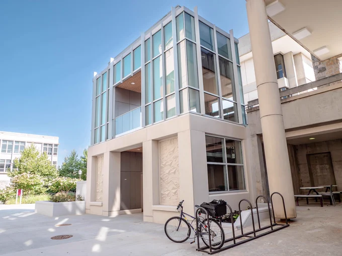 Glass and precast elevator tower next to Johnston Student Center. A bike rack is next to the tower. 