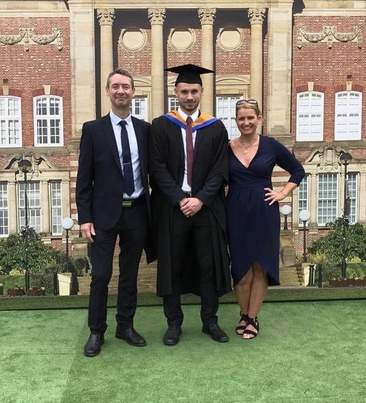 Callum with his parents when he graduated from Leeds Beckett University with a First-Class Honours Degree. He is wearing his graduation gown and hat.