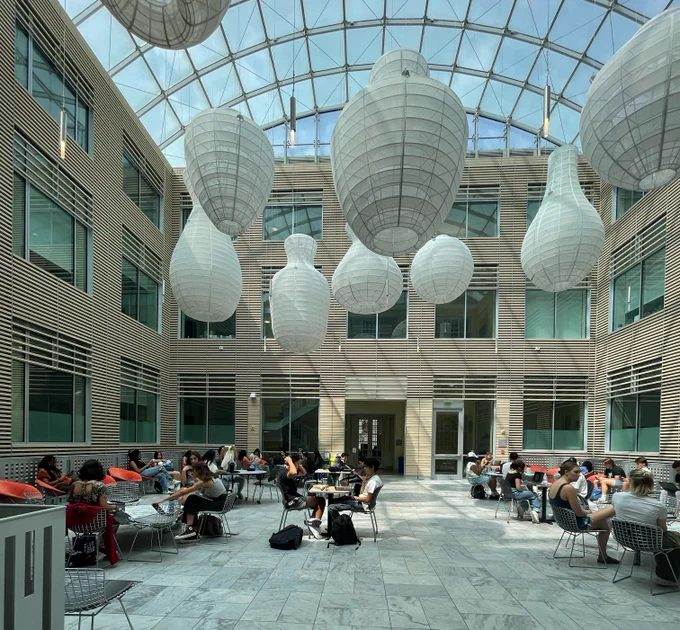 Several students sitting at tables inside a large atrium on the Homewood campus.