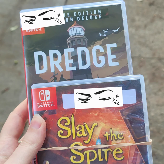 picture of sooch's real not cartoon human hand holding a copy of Dredge and Slay the Spire