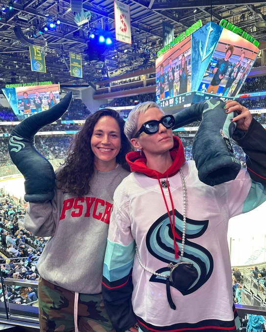 Sue Bird & Megan Rapinoe at a Kraken game and posing for a photo together

Both have tentacle plushie fingers on and Megan has a white kraken jersey on 