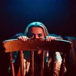 A woman peeks over the back of a chair